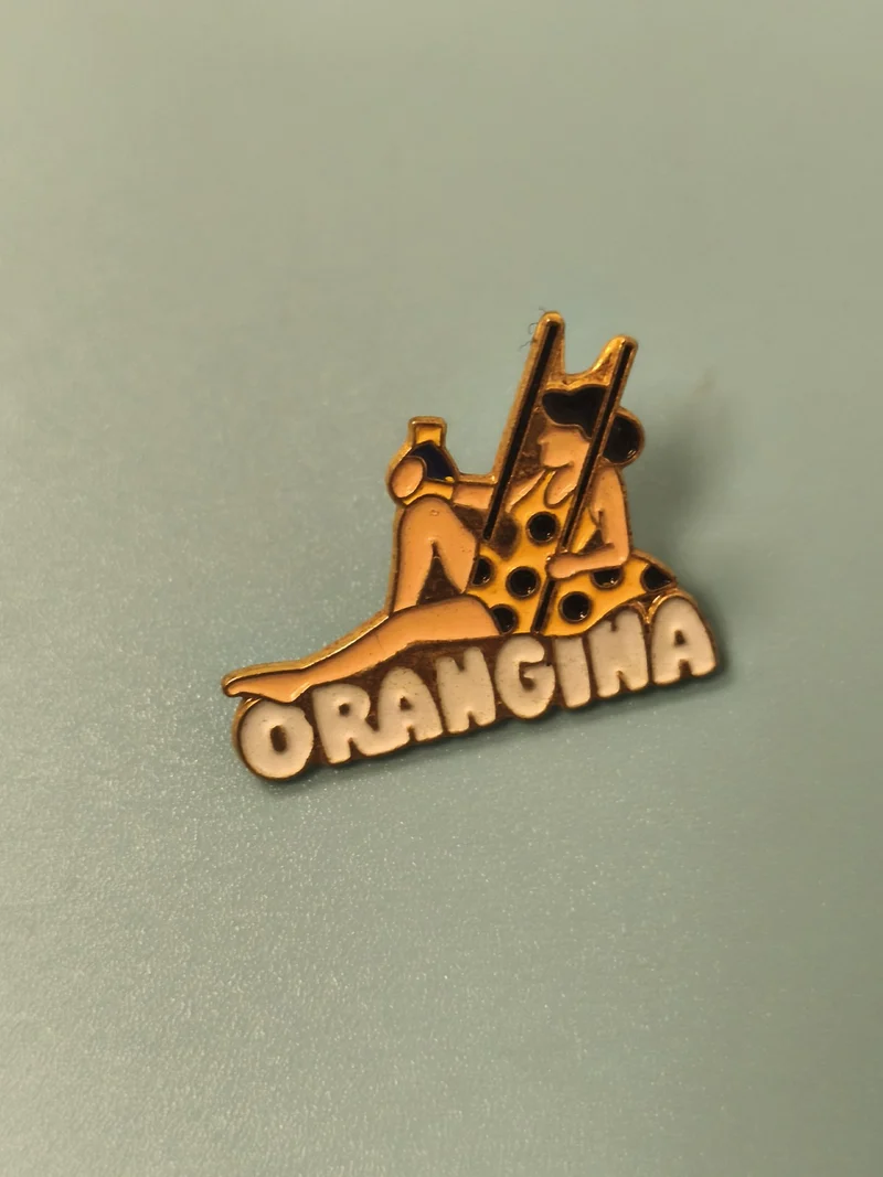 Pin's vintage Orangina publicitaire, personnage assis, collection badge ancien