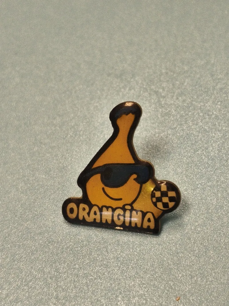 Vintage pin's Orangina logo bouteille jaune lunettes, objet publicitaire rétro