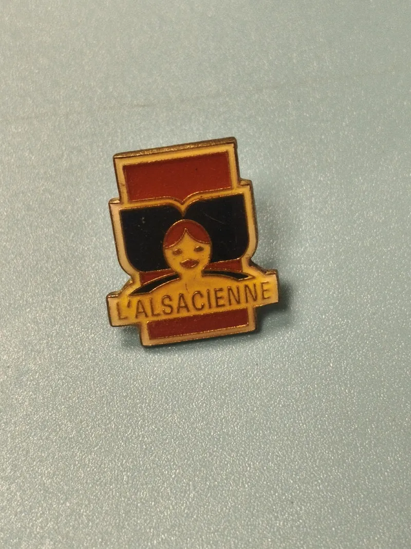 Vintage pin's publicitaire L'Alsacienne, visage stylisé, collection badge ancien