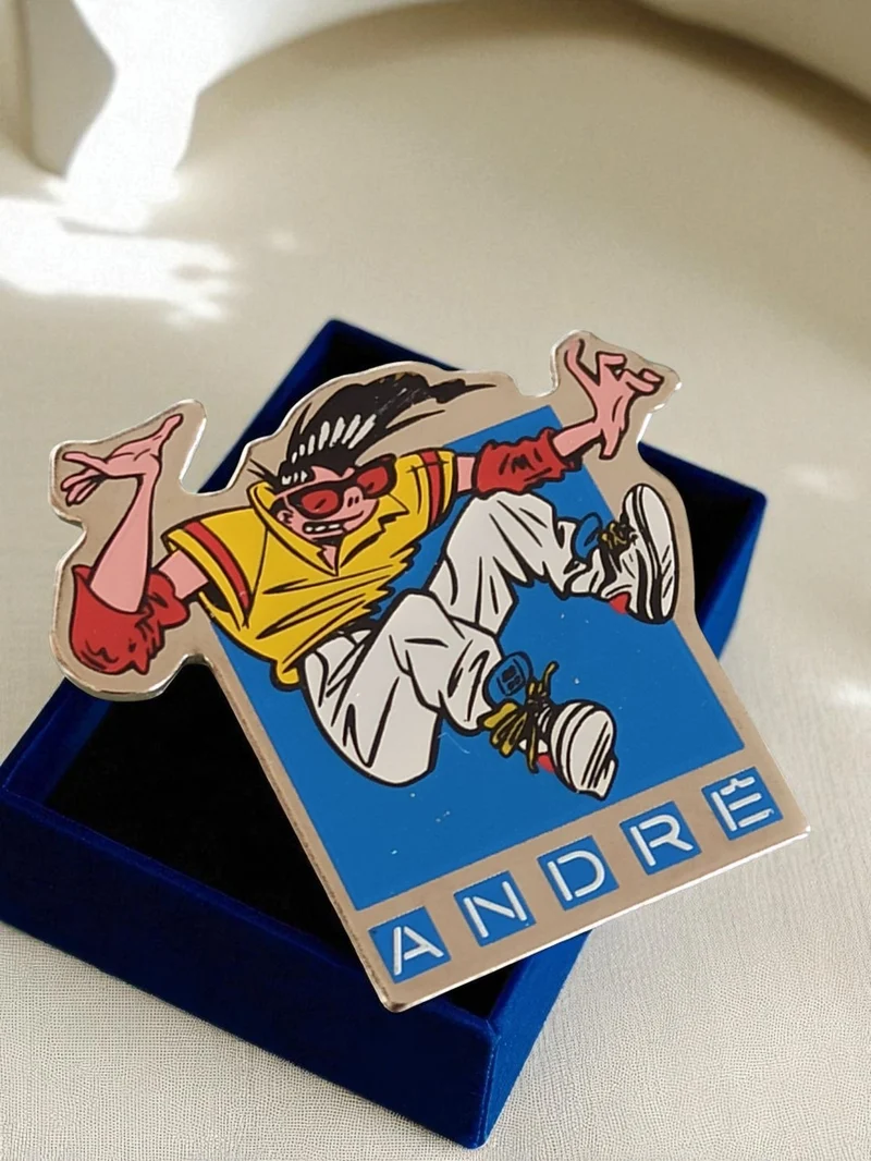 Pin's publicitaire vintage ANDRÉ années 90 style BD, badge émaillé coloré