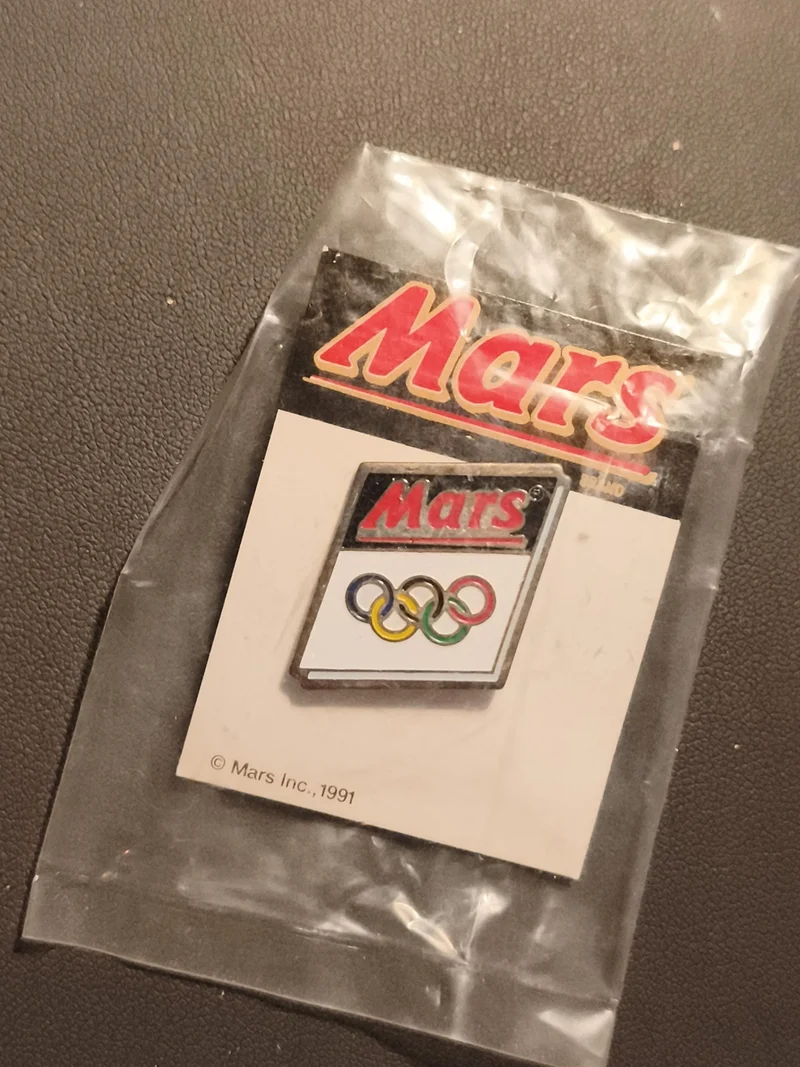 Pin's Mars Jeux Olympiques 1991 logo anneaux olympiques sous blister