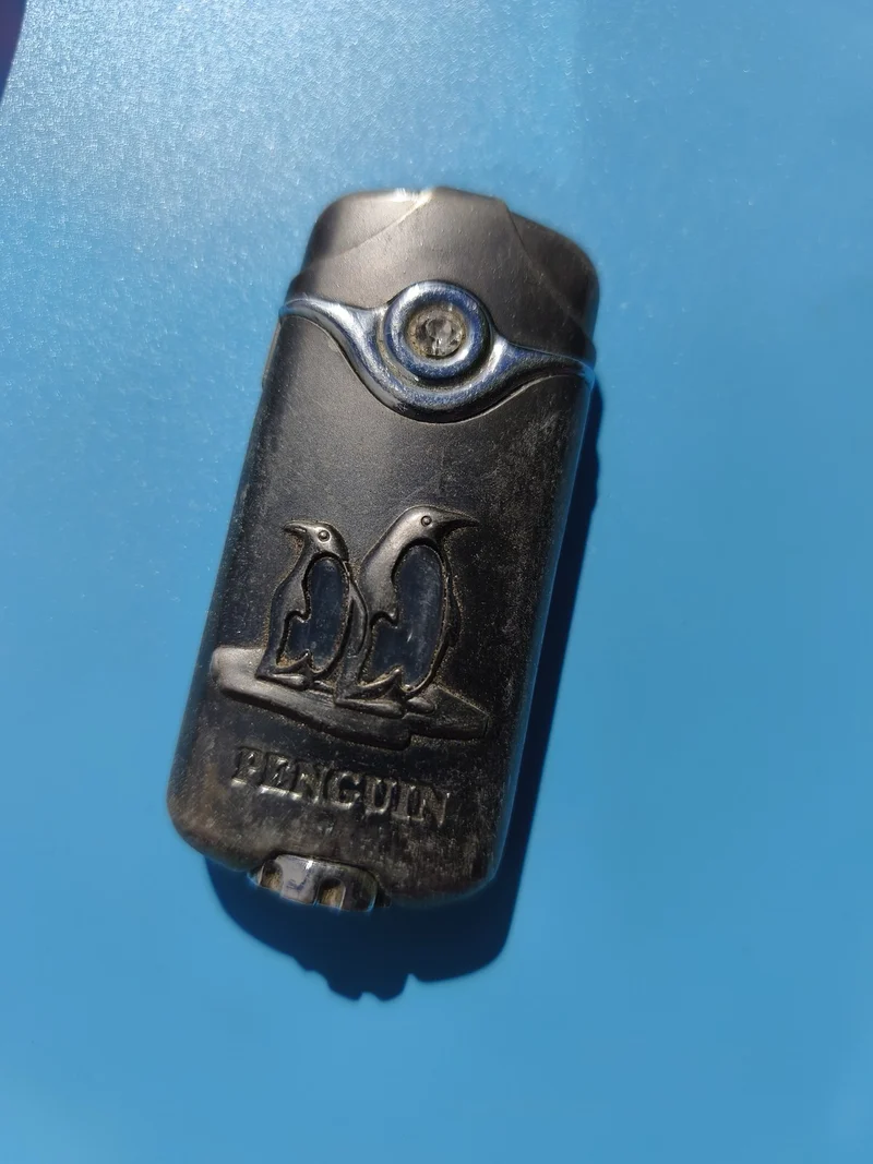 Ancien briquet publicitaire Penguin, motif pingouins, métal, à restaurer