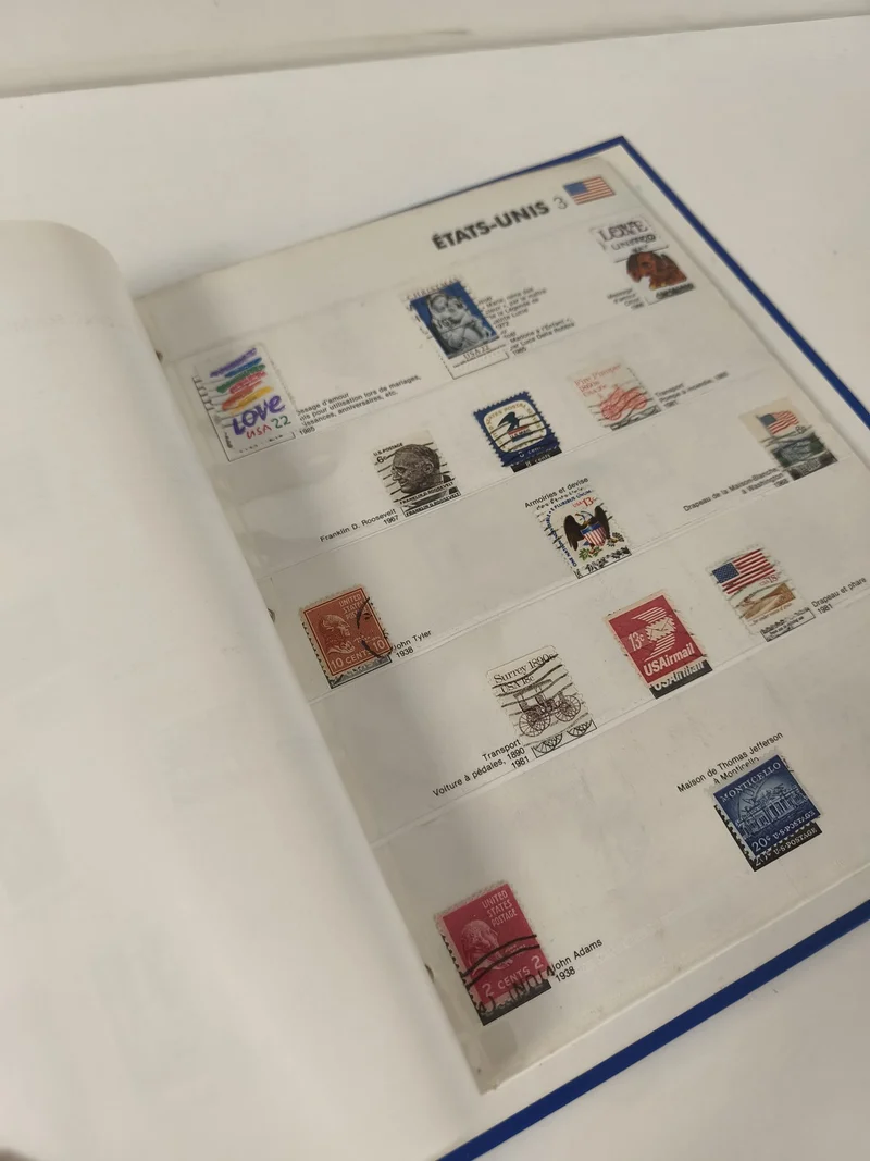 Classeur de timbres partiellement rempli, pages thématiques, couverture bleue