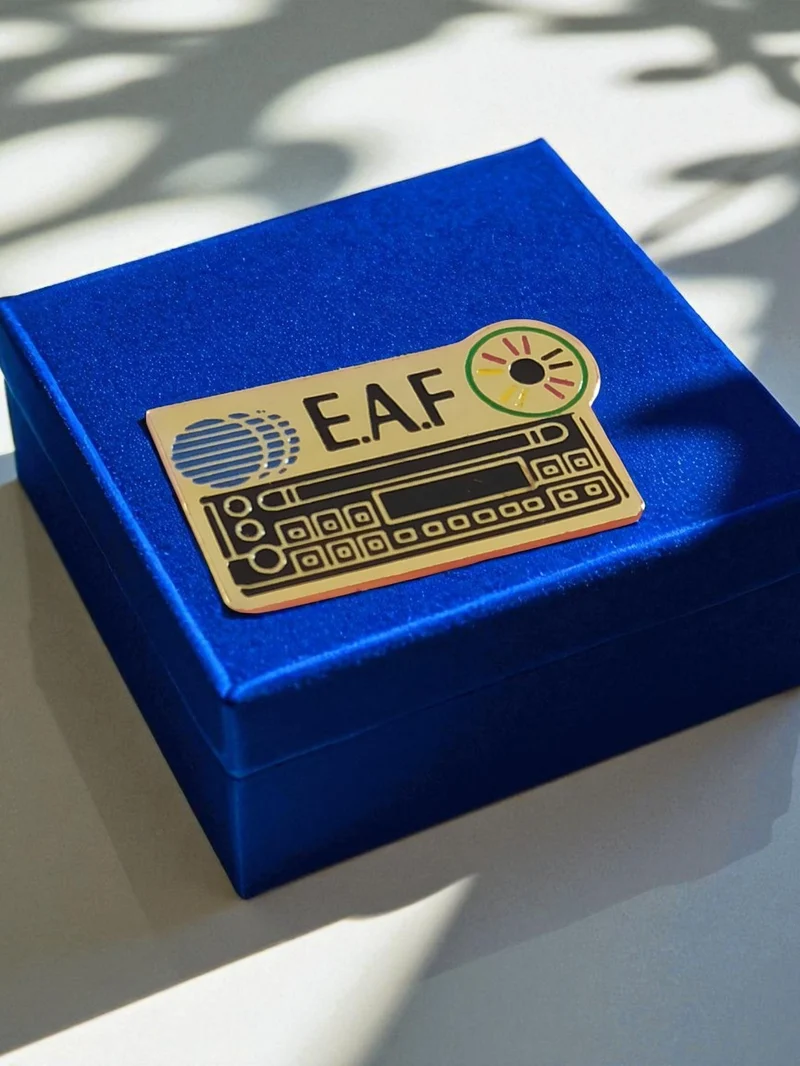 Pin's vintage émail E.A.F. logo disque doré années 80 badge publicitaire